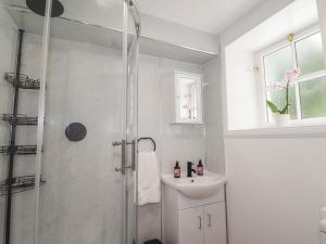 a white bathroom with a shower and a sink at Station Lodge in Forres +18 photos