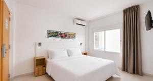 a white bedroom with a white bed and a window at Hotel Las Vegas in Calella