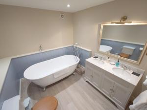 a bathroom with a tub and a sink and a mirror at The Fox at Ibstone in High Wycombe