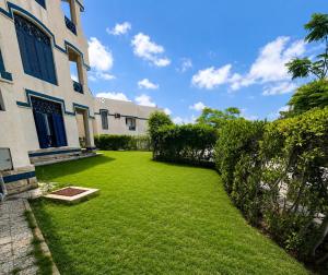 a yard with green grass next to a building at Charming 3BDR Chalet l North Coast in Dawwār Muşādif Yūnus