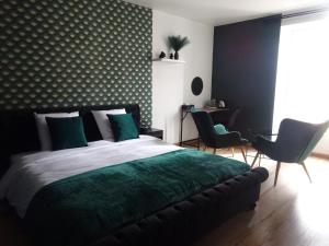 a bedroom with a bed with green sheets and chairs at Les Précieuses in Réaumur