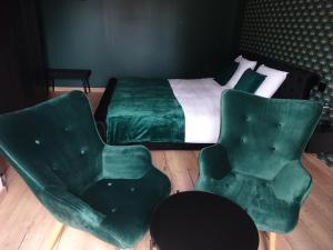 a bedroom with a bed and two green chairs at Les Précieuses in Réaumur +4 photos