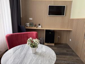 a room with a table with a vase of flowers on it at Hotel TheCorner in Konstanz +18 photos