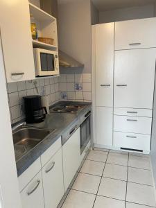 a kitchen with white cabinets and a sink and a microwave at Ferienhaus Wind & Welle in Norddeich +9 photos
