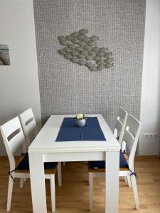 a white table with four chairs and a blue table cloth at Ferienhaus Wind & Welle in Norddeich