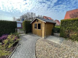 a small wooden shed sitting next to a hedge at Ferienhaus Wind & Welle in Norddeich
