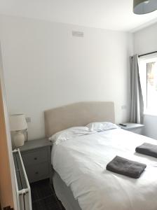 a bedroom with a white bed with two towels on it at The Townhouse Self Catering in Dumfries +72 photos