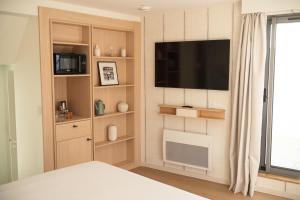 a bedroom with a bed and a flat screen tv at Domaine des Grands Sables, Île Groix - Handwritten Collection in Groix