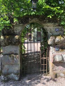 an iron gate in a stone wall with a street at la maison oubliée in Goetzenbruck