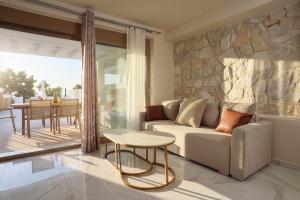 a living room with a couch and a stone wall at The Serata Villas in Hanioti