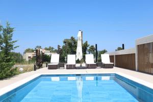 a swimming pool with lounge chairs and a umbrella at The Serata Villas in Hanioti +42 photos
