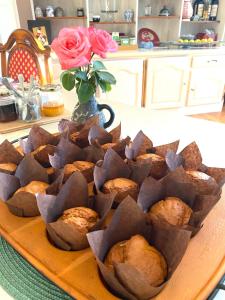 a plate of muffins on a table with a vase of roses at O Jardin Sakura Chambres et table d'hotes sur la route du Mont Saint-Michel in Val Couesnon +17 photos