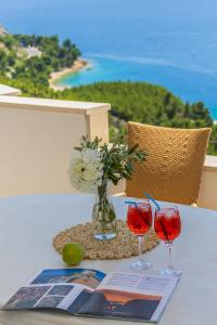a table with two glasses of wine and a book at White Cove Apartments in Lokva Rogoznica