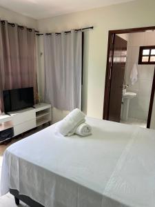 a bedroom with a bed with a television and a bathroom at Casa Flora & Mar in Pipa