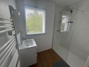 a white bathroom with a shower and a sink at Studio indépendant à notre maison in Concarneau