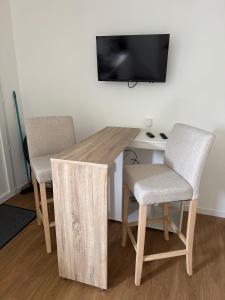 a wooden desk with two chairs and a television on a wall at Studio indépendant à notre maison in Concarneau