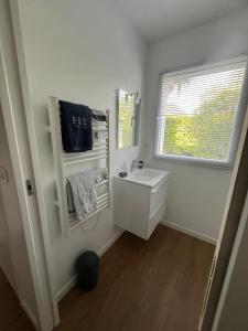 a white bathroom with a sink and a window at Studio indépendant à notre maison in Concarneau