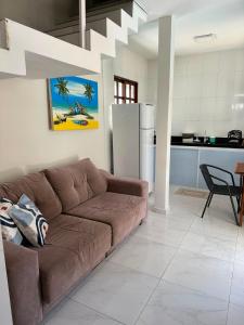 a living room with a brown couch and a kitchen at Casa Flora & Mar in Pipa