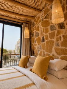 a bed in a room with a stone wall at Palm Surf & Spa Hotel in Agadir