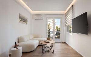 a living room with a white couch and a table at Vouliagmeni Olivomare Suite in Athens