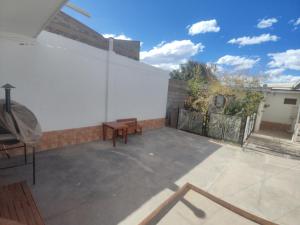 a patio with a bench and a white wall at Hostal La Candelaria in Humahuaca