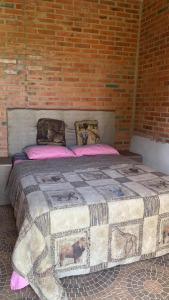a large bed with pink pillows and a brick wall at Villa Virgen De La Gracia in Tobatí