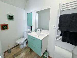 a bathroom with a white toilet and a sink at La Palmeraie, Duplex in Bar-le-Duc