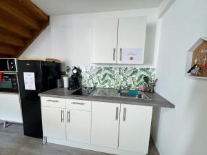 a kitchen with white cabinets and a black refrigerator at La Palmeraie, Duplex in Bar-le-Duc