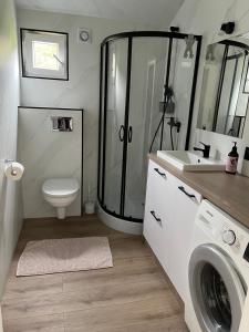 a bathroom with a shower and a washing machine at Domek pod brzozami in Waszki