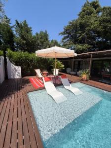 a swimming pool with two chairs and an umbrella and an umbrella at Maison AdriAnna in Vedène