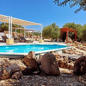 a swimming pool in a yard with rocks around it at Pasare Glamping_AnglonaRuralExperience in Perfugas