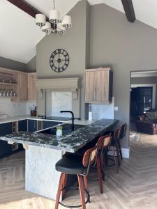 a kitchen with a counter with chairs and a clock on the wall at Creagh Road House in Ballinrobe