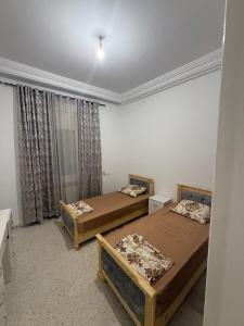 a bedroom with two beds and a window at Aouina Stay in El Aouina Station