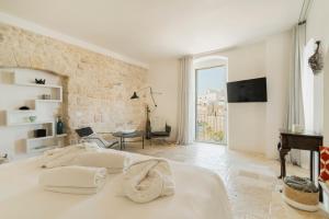 a white bedroom with a large bed and a living room at Antico Mondo Rooms & Suites in Polignano a Mare