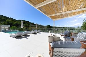 a patio with lounge chairs and a swimming pool at Villa Emerald Diamond in Kolios