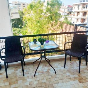 a glass table on a balcony with two chairs at Studio Nicki Chania in Chania