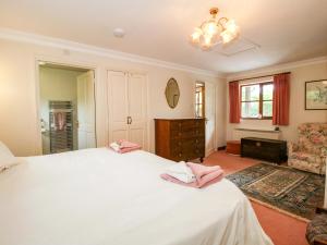 a bedroom with a large white bed with pink towels on it at Willow Cottage in North Lydbury