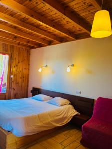 a bedroom with a bed and a red chair at Hôtel du Mont Bar in Allègre