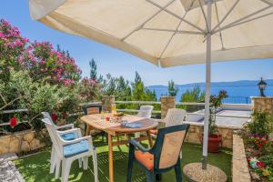 a patio with a table and chairs and an umbrella at White Cove Apartments in Lokva Rogoznica