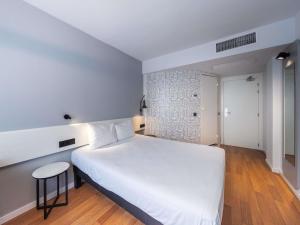 a bedroom with a large white bed and a stool at Ibis Murcia in Murcia