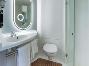 a bathroom with a toilet and a sink and a mirror at Ibis Murcia in Murcia