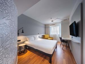 a bedroom with a bed and a desk and a tv at Ibis Murcia in Murcia