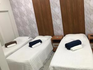 three beds in a room with white sheets and blue pillows at Hotel Familiar in Salinas