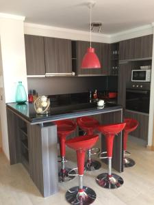 una cocina con taburetes rojos en un mostrador negro en Solvallerios Viña Centro, en Viña del Mar