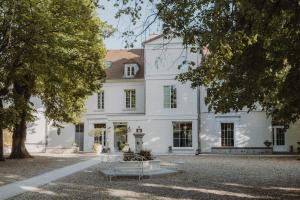 a white house with trees in front of it at Les Demeures de Varennes, BW Signature Collection in Varennes-Jarcy
