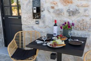 a table with a plate of food and a bottle of wine at Argolis Rodies Homes in Kilada