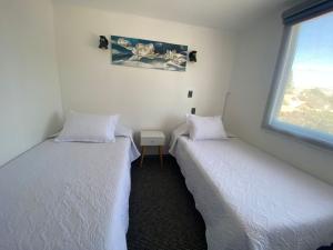 two twin beds in a room with a window at Amoblados Copiapo in Copiapó