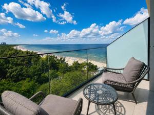 a balcony with chairs and a table and a beach at Baltic Infinity Suite 529 - SPA & Pool Access in Międzyzdroje