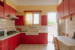 a kitchen with red cabinets and a table in it at Anna Christina in Kamena Vourla