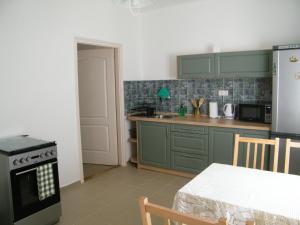 a kitchen with green cabinets and a table and a stove at Sártekerő Vendégház in Alsópáhok